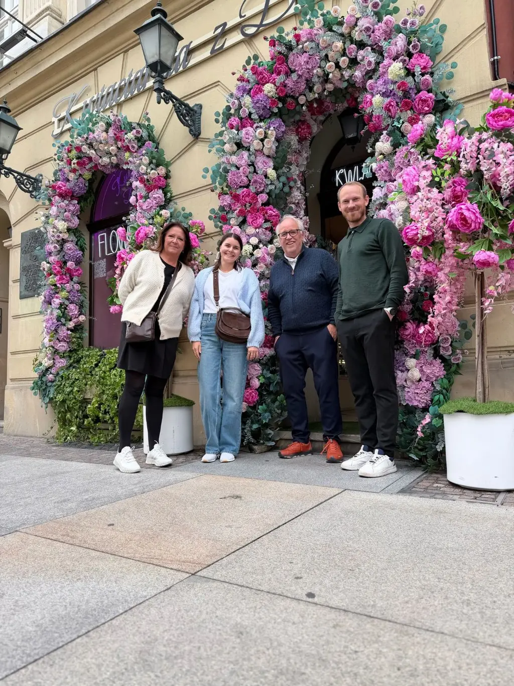 Fire kolleger foran en inngang dekorert med rosa blomster